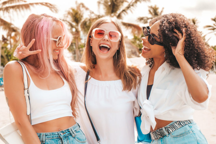 3 femmes avec coiffure d'été devant la plage avec un grand sourire